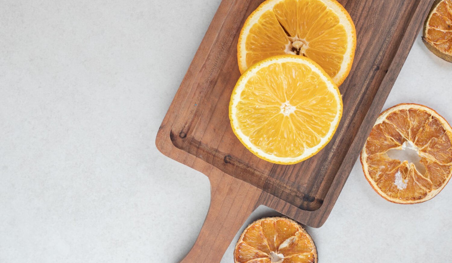 Rodajas de naranja frescas y secas sobre una tabla de madera